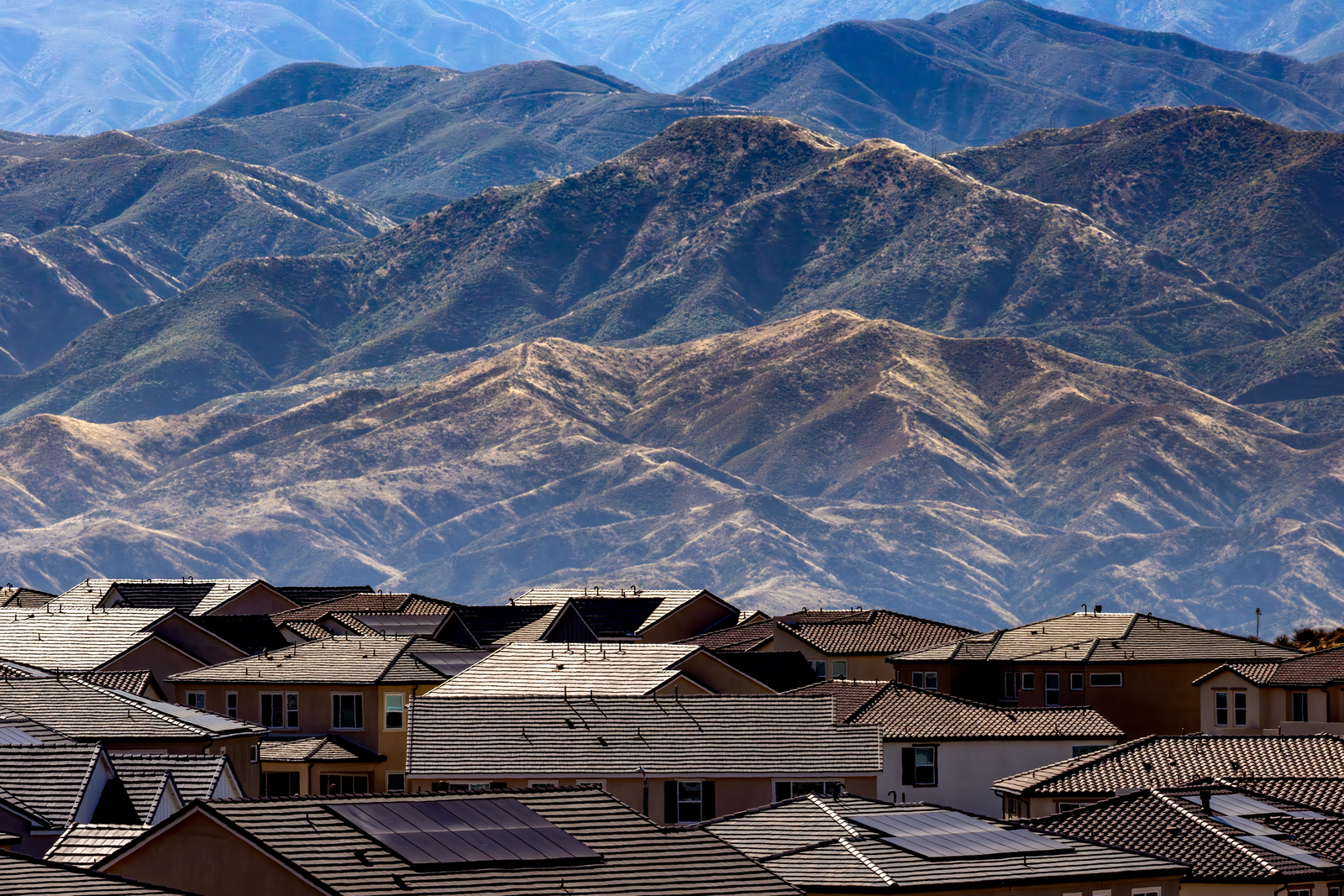 Rows of suburban rooftops with hills in the background